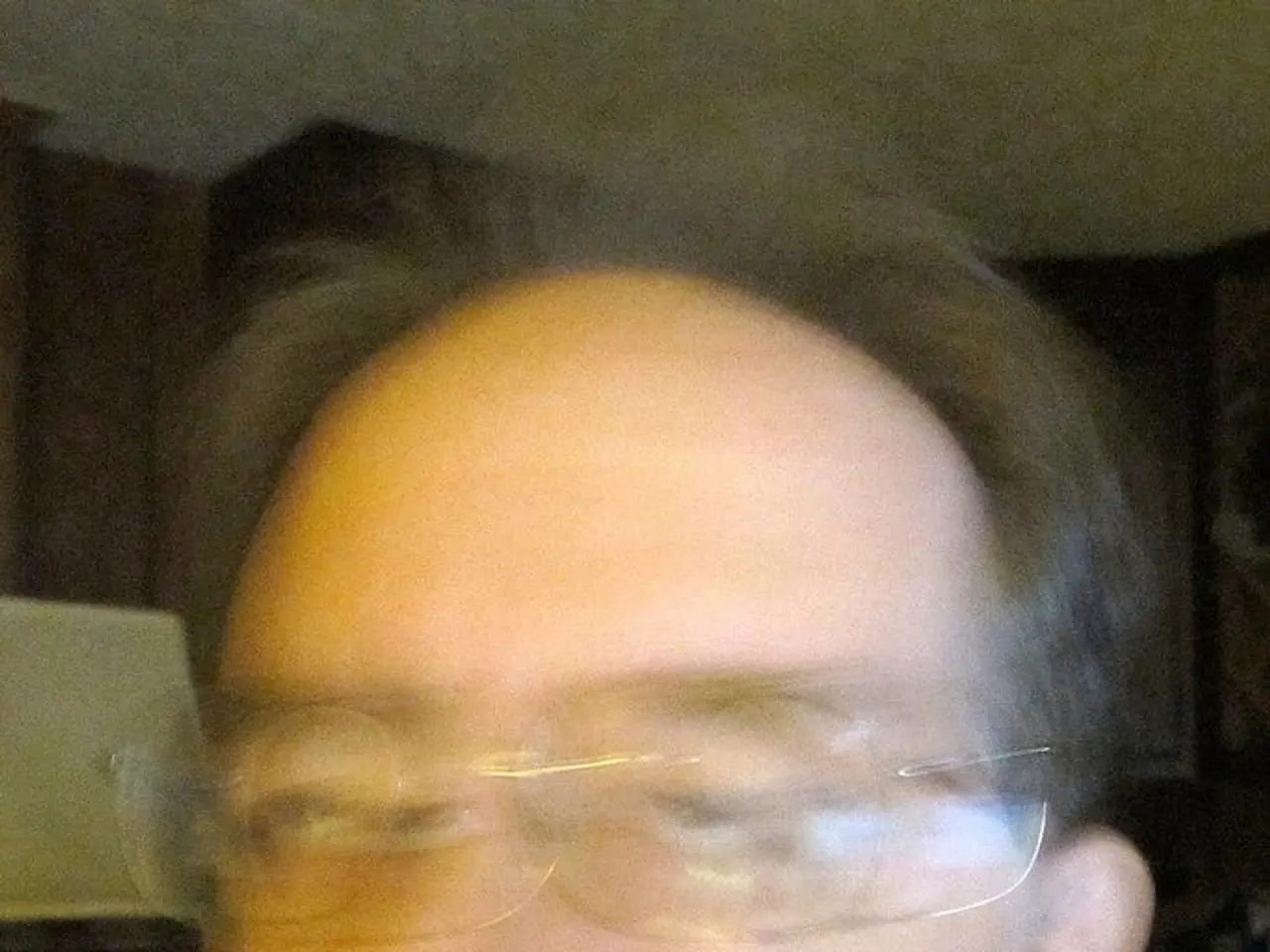 In the picture I can see a man is wearing spectacles. This picture is blurred.