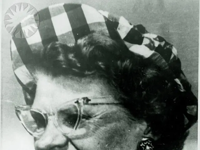 In the image, we can see a woman. She is laughing, she is wearing spectacles and she is wearing...