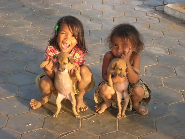 There are 2 kids holding each a dog in their hands.