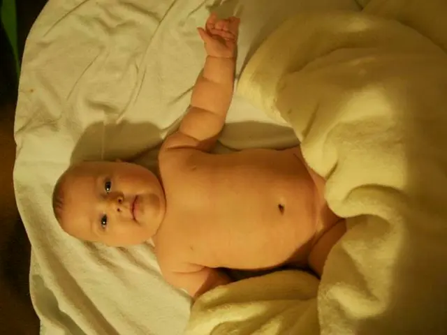 In the center of the image we can see one baby sleeping. On the baby, we can see one blanket.