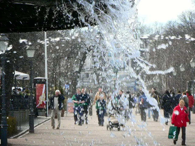 In this image I can see water is spilling, at the bottom group of people are walking on the road....