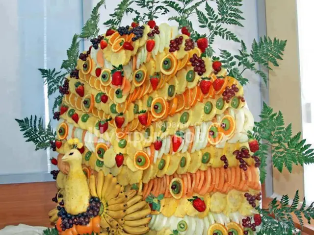 In this picture we can see a peacock shaped salad decorated with green leaves at the top.