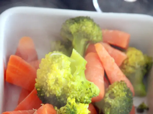 In the foreground of this image, there are pieces of carrot and broccoli in a bowl like an object.